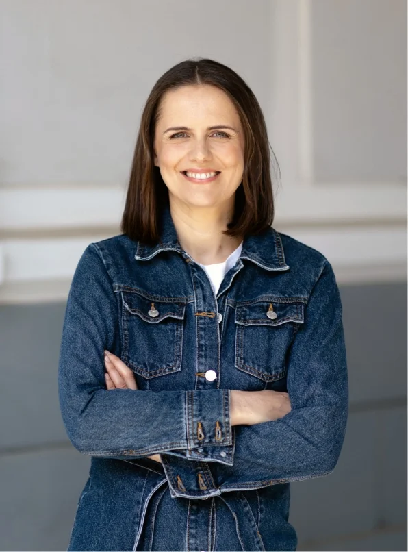Frau mit Jeansjacke lächelt in die Kamera.